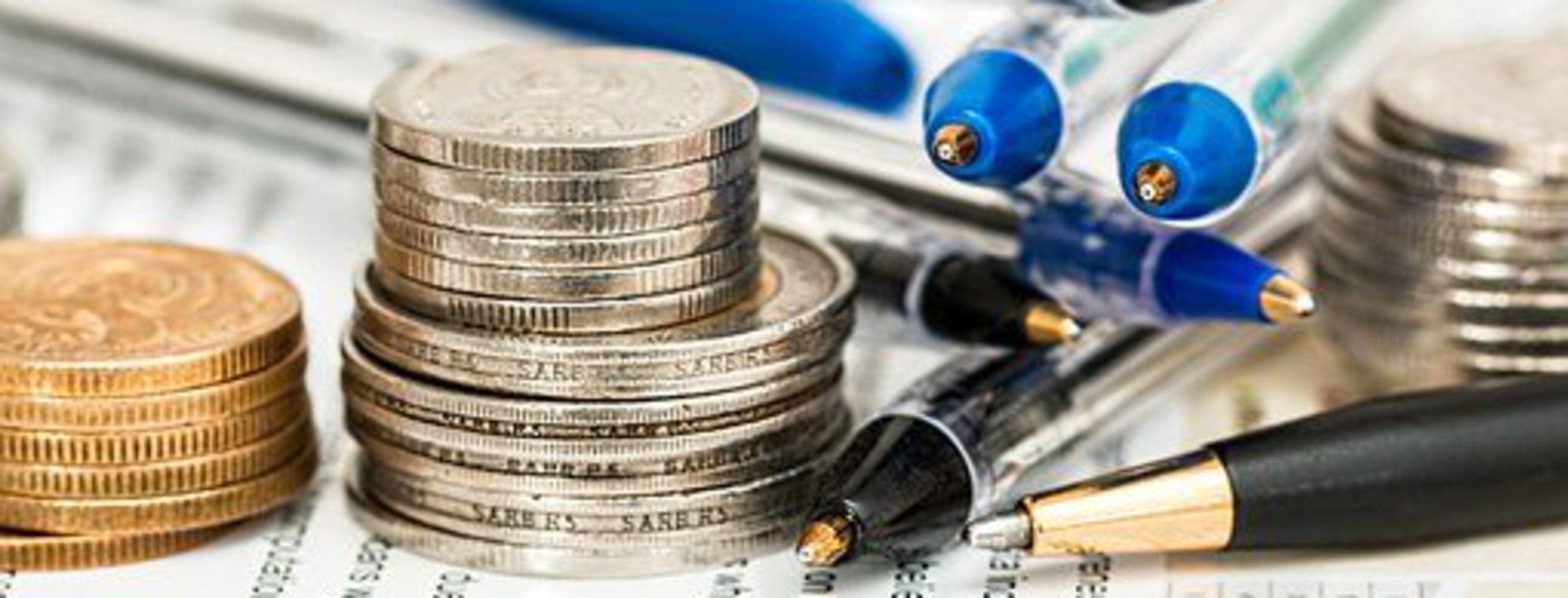 En bild på små högar med mynt och pennor på ett papper med text på