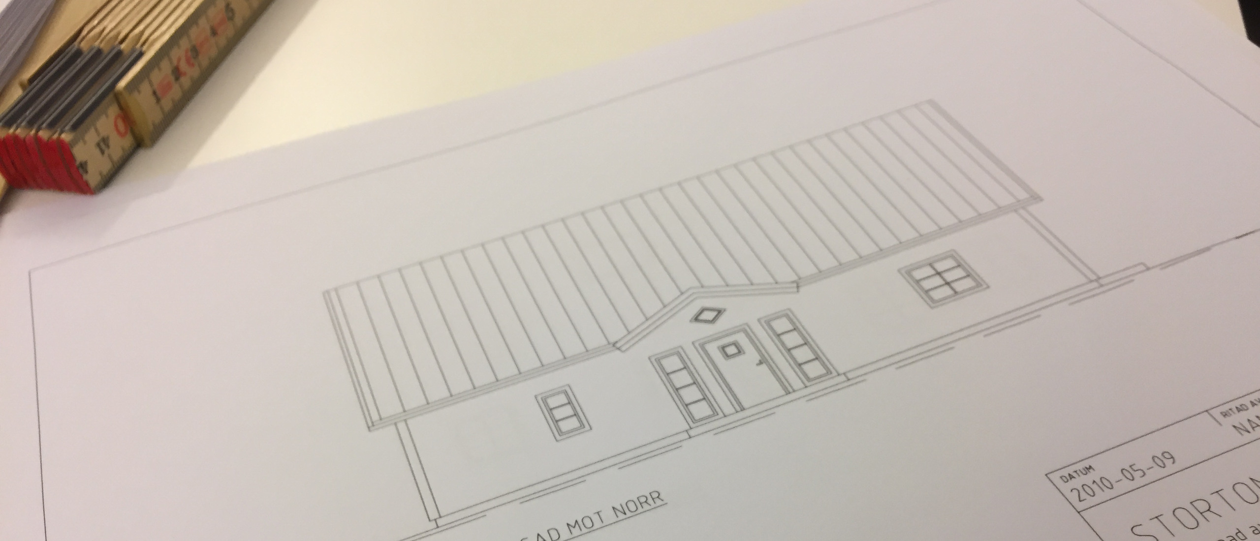 En ritning av ett villahus på ett skrivbord.