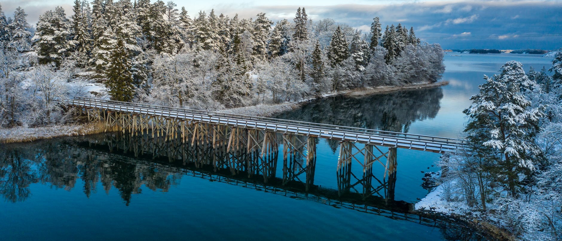 Bild visar en träbro mellan två öar  vintertid i Sankt Annas skärgård.