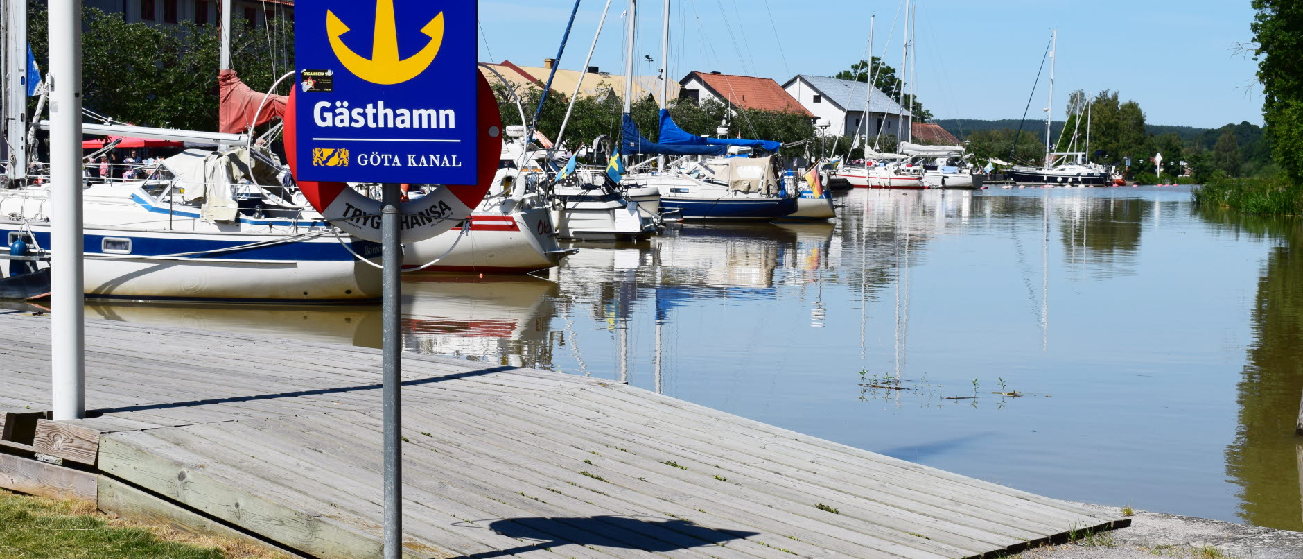 Bild visar en *Gästhamnsskylt framför en brygga med båtar i Göta kanalhamnen i Söderköping.